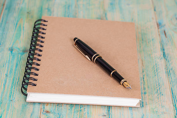 istock selective focus of the  pen on opened lined diary book , 590038452