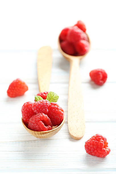 istock Red raspberries in spoon on a white wooden table 590039532
