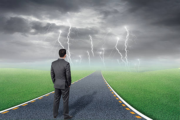 istock Businessman standing in road leading to storm 590040748