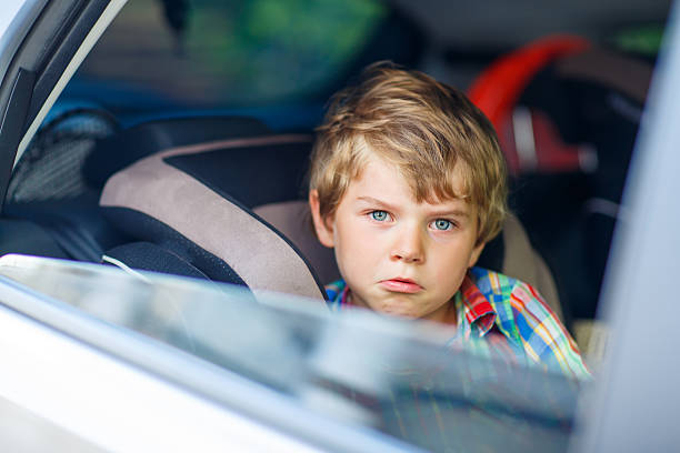 istock Sad tired kid boy sitting in car  during traffic jam 590041256