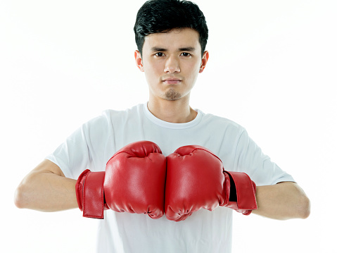 Young man in boxing gloves and a white sweatshirt on a dark background in the studio. The concept of victories and battles.