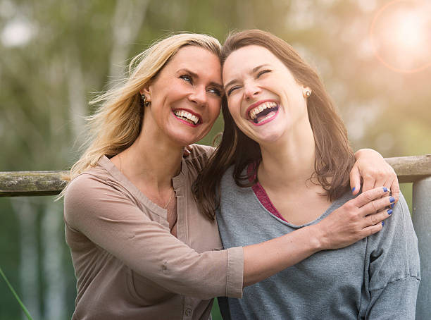 two woman laughing and hugging each other outdoors two woman hugging each other outdoors and laughing mom and sister stock pictures, royalty-free photos & images