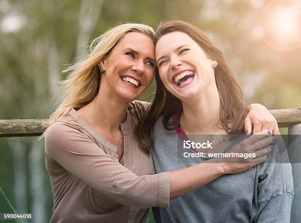 Two Woman Laughing And Hugging Each Other Outdoors Stock Photo - Download Image Now - Girlfriend, Friendship, Two People