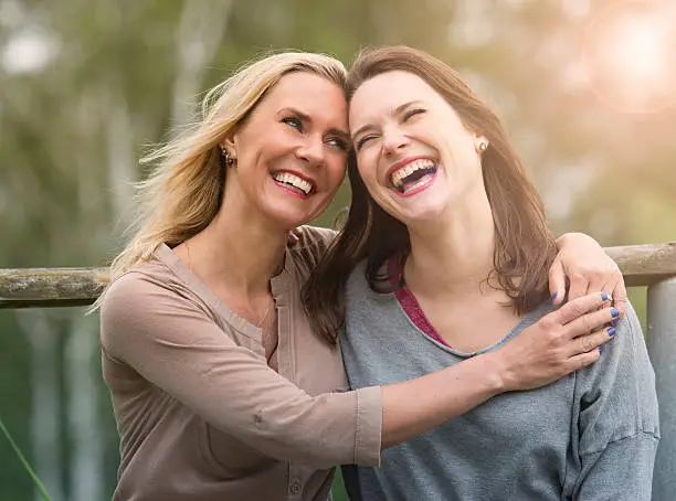 two woman hugging each other outdoors and laughing