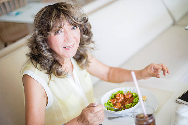 Senior woman eating at the restaurant stock photo