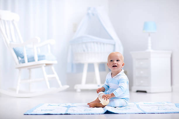 istock Baby boy drinking milk in sunny nursery 590044304