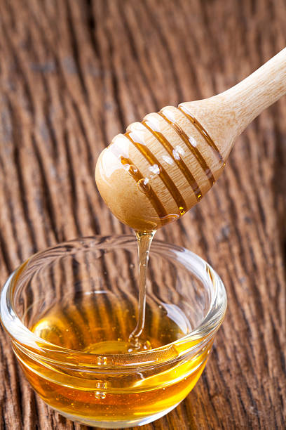 istock Honey bowl with dipper and flowing honey 590045306