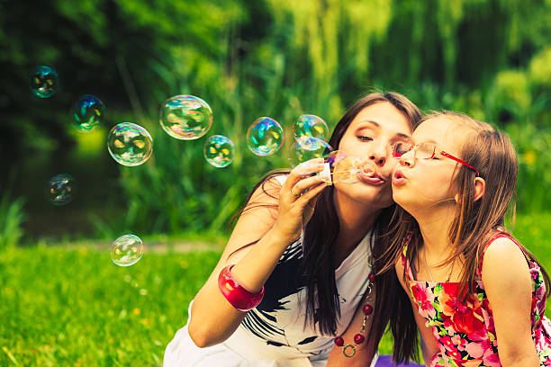 istock Mother and child blowing soap bubbles outdoor. 590045502