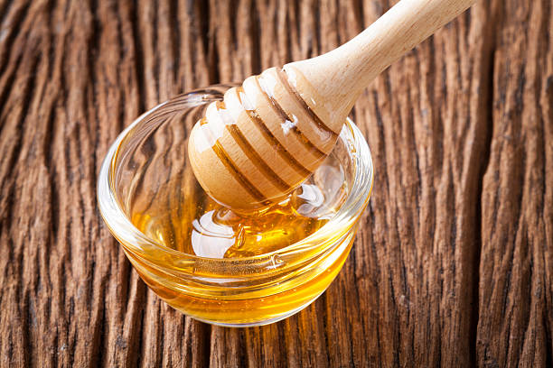 istock Honey bowl with dipper and flowing honey 590045520