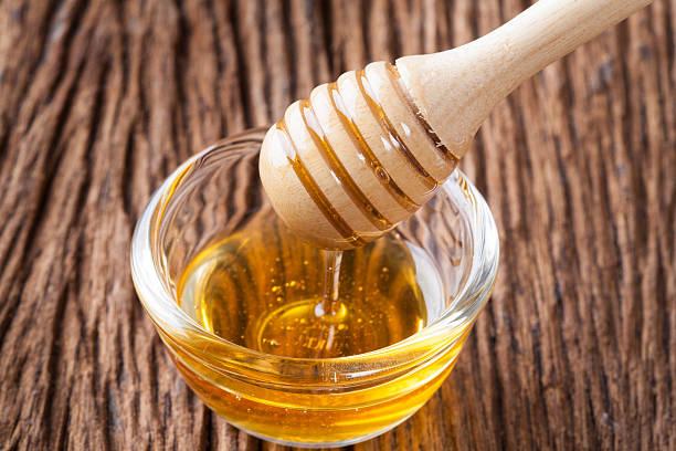 istock Honey bowl with dipper and flowing honey 590045684