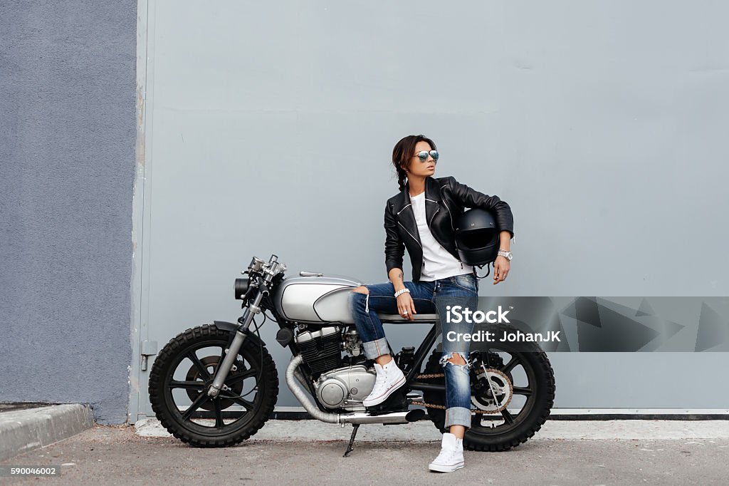 Biker woman in leather jacket on motorcycle Outdoor lifestyle portrait of sexy biker girl sitting on a vintage custom motorcycle Motorcycle Stock Photo
