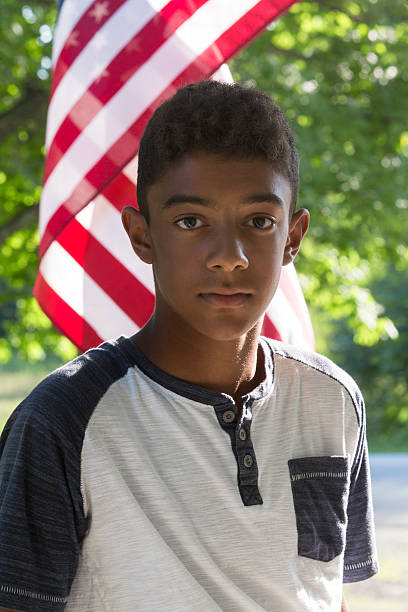 istock Serious Mixed Race Boy in Front of American Flag 590046094