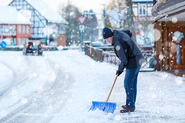homme avec pelle à déneiger cleans les trottoirs en hiver - warmly photos et images de collection