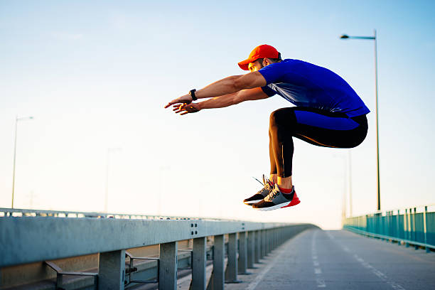Image of young muscular male doing exercises outdoors on summer day, keeping body in fit shape. Athlete is jumping onto the barriers. Image taken with Nikon D810 and developed from RAW.
