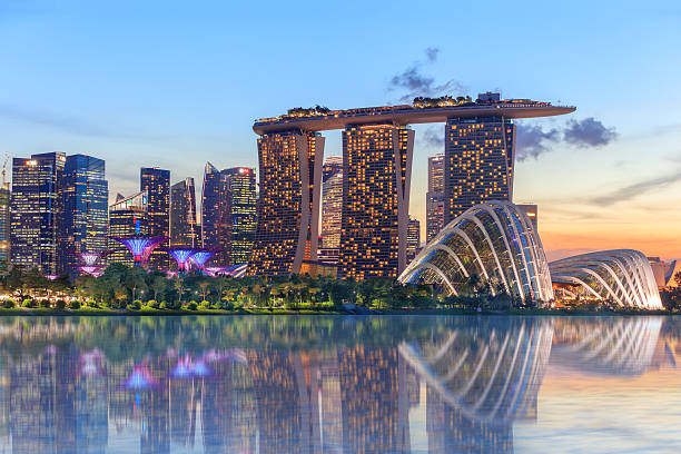 Singapore glowing at night Singapore, Republic of Singapore - May 4, 2016: Supertree grove, Cloud garden greenhouse and Marina Bay Sands hotel reflecting in water at dusk with glowing lights elevated walkway photos stock pictures, royalty-free photos & images