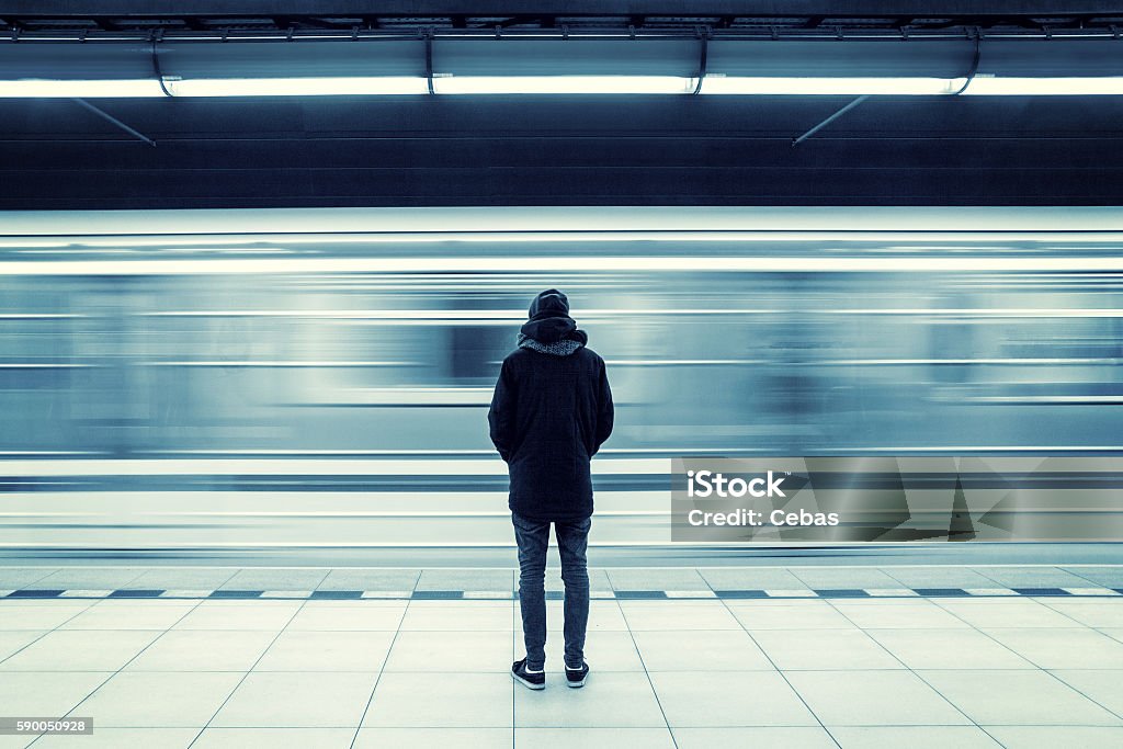 Man at subway station Lonely young man shot from behind at subway station with blurry moving train in background Train - Vehicle Stock Photo