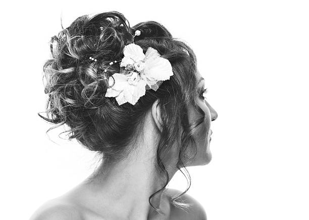bride holds flovers in hand, stands back on the beach