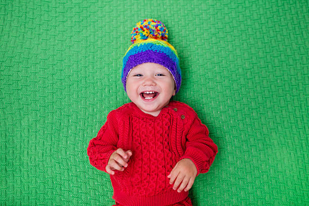 istock Little baby in warm knitted hat on a green blanke 590053806