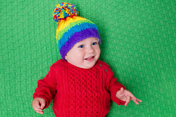istock Cute little baby in warm knitted hat on green blanke 590054376