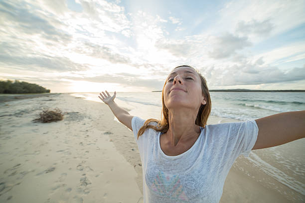 istock Young woman arms outstretched on the beach 590056232