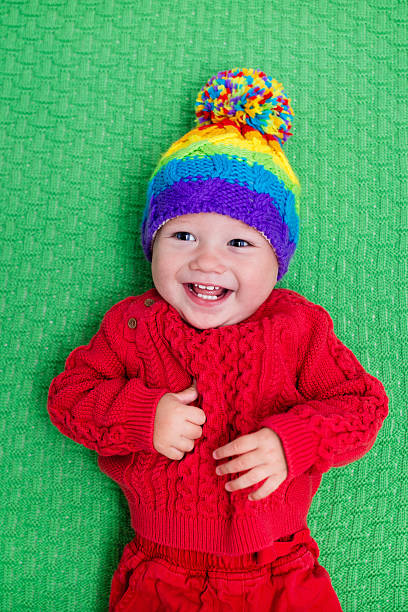 istock Adorable little baby in warm knitted hat on green blanke 590057826