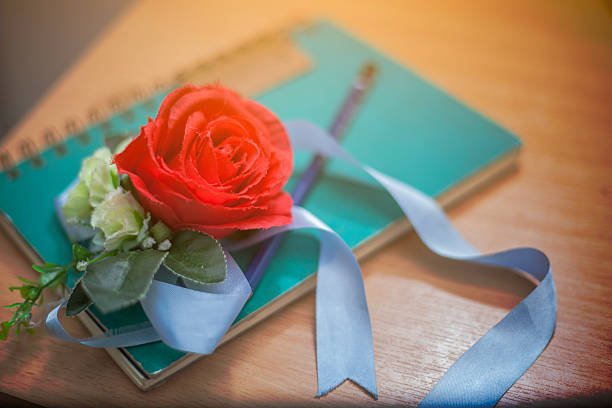 Red roses and notebook on wood background, love concept,vintage colorRed roses and notebook on wood background, love concept