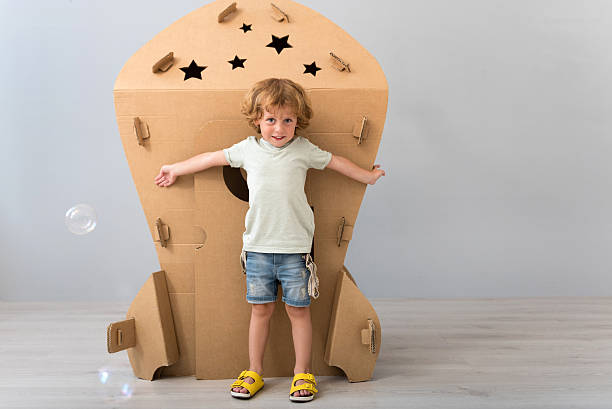 istock Little boy standing near carton rocket 590059346
