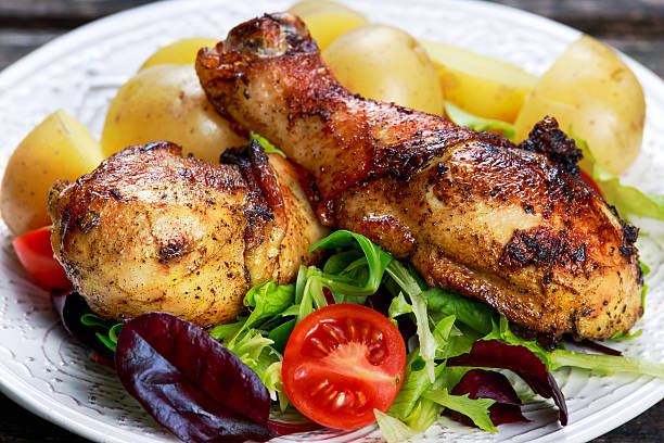 istock Baked chicken legs with potatoes and vegetables 590060220