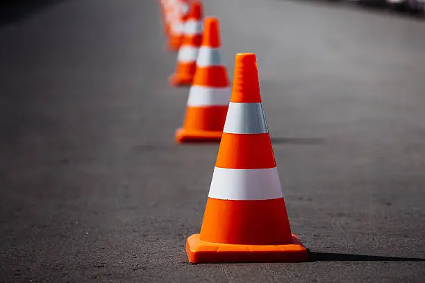 bright orange traffic cones standing in a row on dark asphalt