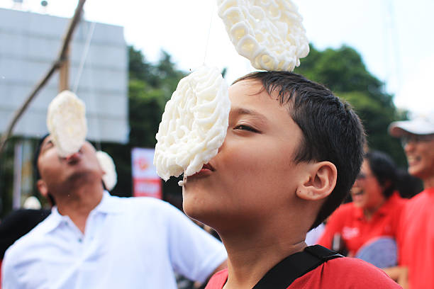 cracker eating contest Jakarta, Indonesia- August 17, 2016: Residents enthusiastically celebrating the independence of Indonesia with various competitions.  Located at Gelora Bung Karno, cracker eating contest present many exciting prizes. eating child cracker asia stock pictures, royalty-free photos & images