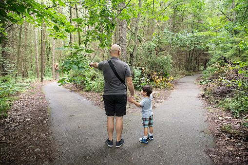 Father and son make a decision about which path to take together while in the woods