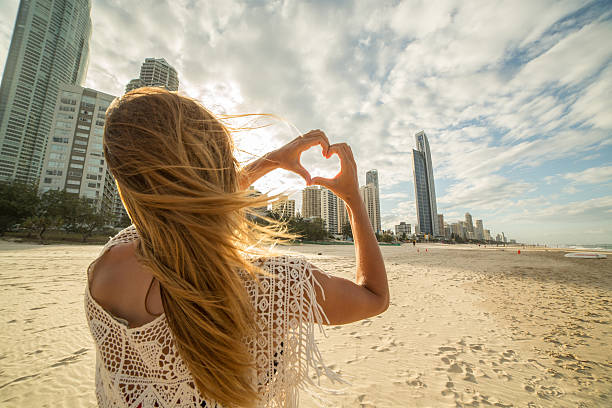 istock Caucasian woman frames Surfers paradise beach into heart shape 590061568