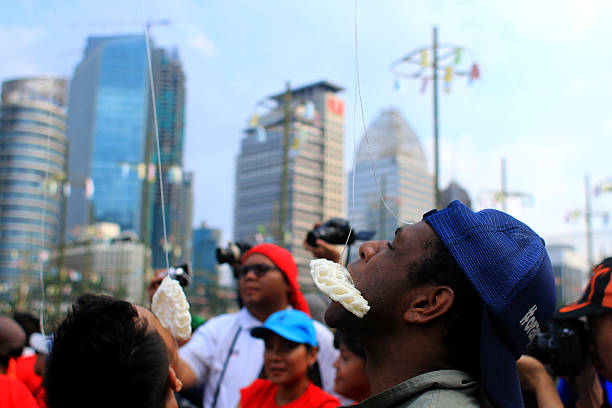 cracker eating contest Jakarta, Indonesia - August 17, 2016: Residents enthusiastically celebrating the independence of Indonesia with various competitions.. Located at Gelora Bung Karno, organized various competitions, cracker eating contest , palm climbing.  There are  present many exciting prizes. eating child cracker asia stock pictures, royalty-free photos & images