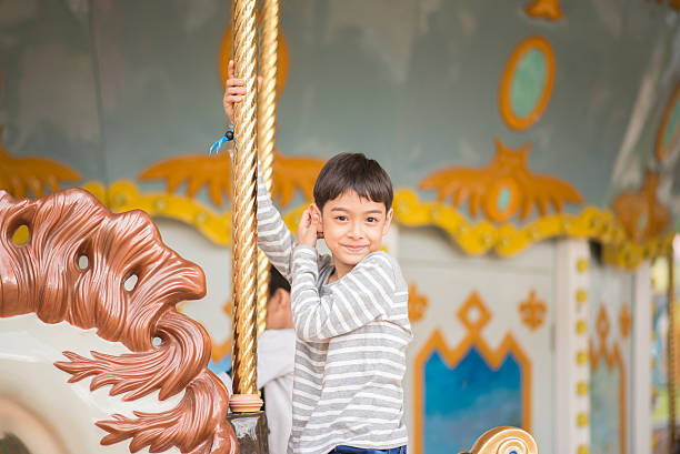 istock Little boy playing in mary go round at fun park 590062546
