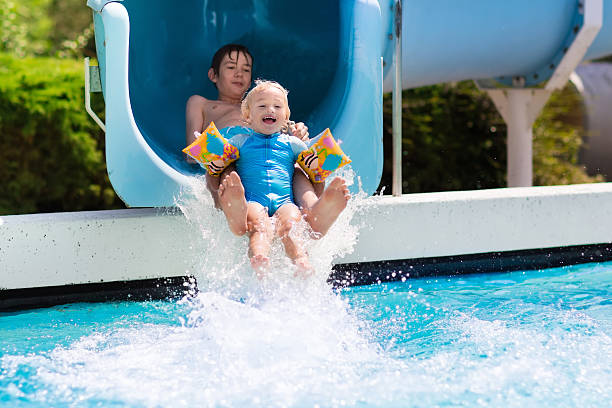 istock Happy kids on a water slide in swimming pool 590063002