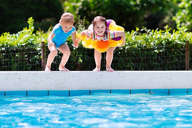 istock Kids jumping into swimming pool in a tropical resort 590063684