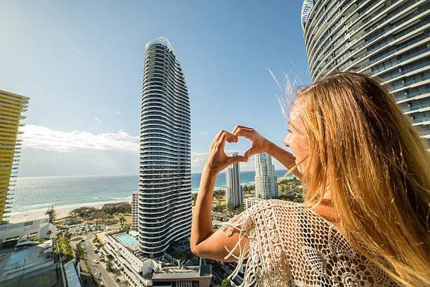 istock Young woman frames Surfers paradise into heart shape finger frame 590063708