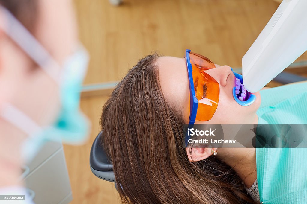 Teeth whitening lamp ultravioleta. The girl on reception at Teeth whitening lamp ultraviolet. The girl on reception at the dentist for teeth whitening. The concept of dental care. Tooth Whitening Stock Photo