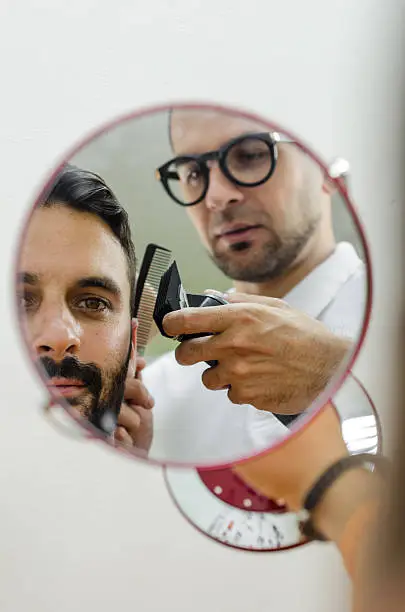 Photo of hairdresser and the client in the reflection mirror