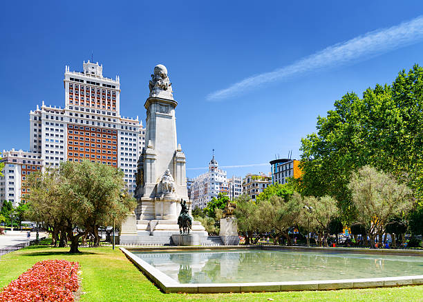 View of the Cervantes monument and the Spain Building (Edificio View of the Cervantes monument and the Spain Building (Edificio Espana) on the Square of Spain (Plaza de Espana) on the blue sky background in Madrid. Madrid is popular tourist destination of Europe. plaza de espana madrid stock pictures, royalty-free photos & images