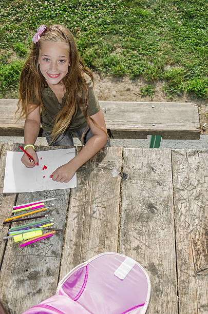 girl doing homework in the park - school bench above bildbanksfoton och bilder