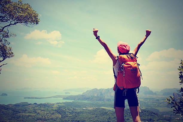 istock cheering successful woman hiker open arms at mountain peak 590072816