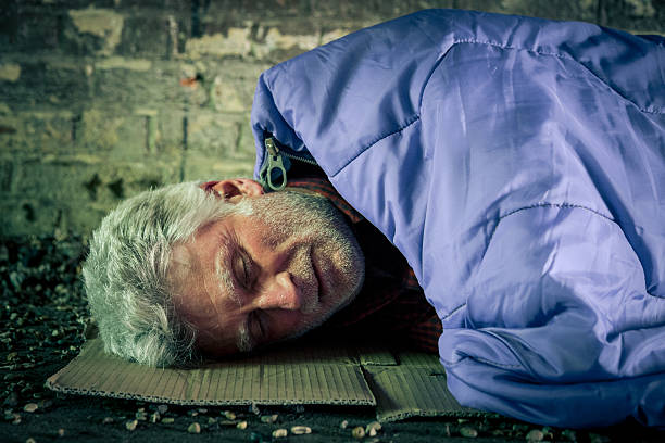 istock Homeless senior man sleeping rough in sleeping bag 590074290