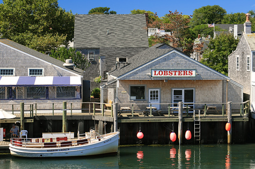 Nantucket, MA, USA - September 5, 2007: Harbor View, Lobster Restaraunt and Moored Boat, Nantucket Island, Massachusetts, USA. Green trees, restaraunt employee and vivid blue clear sky are in the image. Polarizing filter