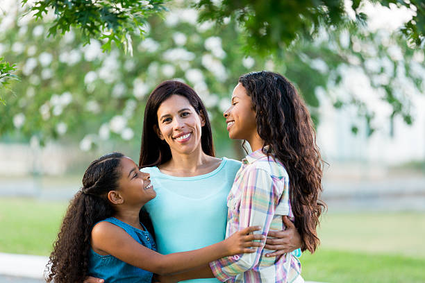 istock Daughters embracing their mother and smiling at each other 590075404