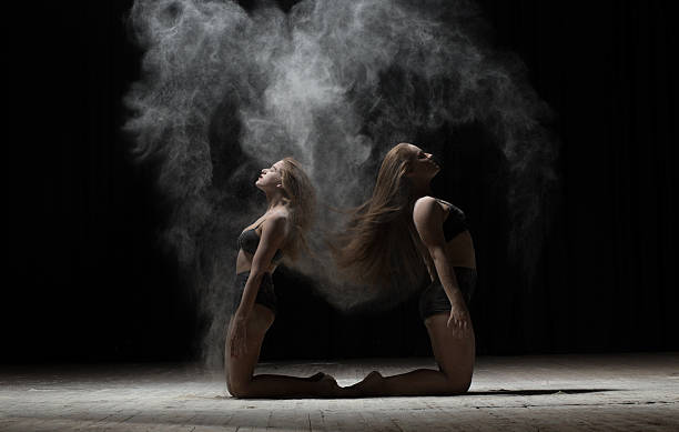 istock Two ballerinas sitting and sprinkle flour on black background 590075434
