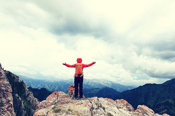 istock cheering successful woman backpacker open arms on mountain peak 590075608
