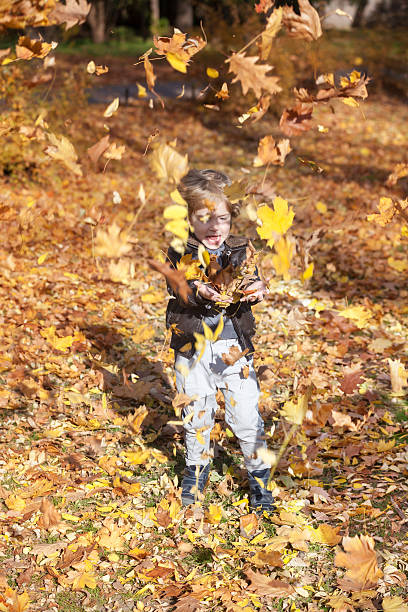 istock Excited boy throwing autumn leaves. 590075804