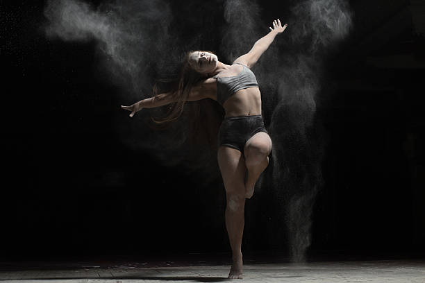istock Flexible woman dancing and sprinkle flour on black background 590075876