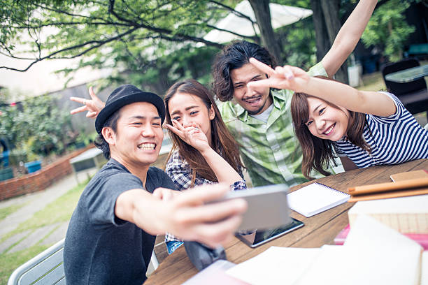 Selfie in the park Group of Japanese students making selfie with mobile phone instead of studying. self portrait stock pictures, royalty-free photos & images